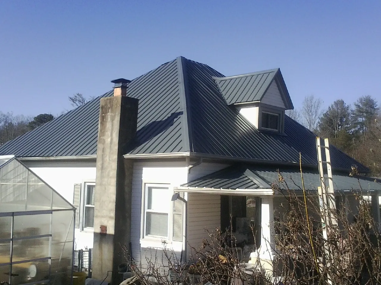 Dark blue standing seam metal roof on a white farmhouse with dormer — Slate & Tile Roof Repair by Roofing Brothers in Louvale