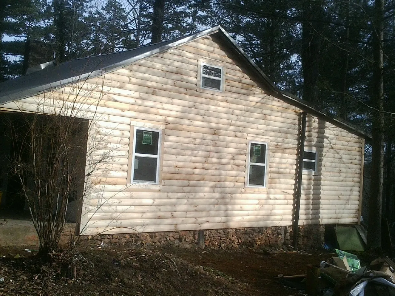 New log siding and dark metal roofing on a gable end in Louvale