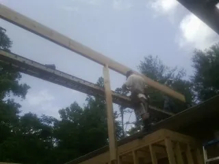 Carpenter setting a ridge beam over a new addition frame — Ice Dam Removal by Roofing Brothers in Louvale