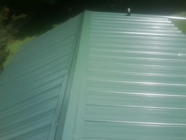 New green metal panels meeting at the ridge of a roof — Flat Roof Repair work by our crew in Louvale