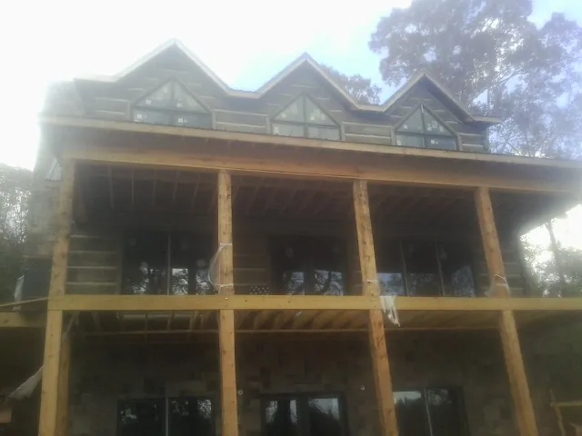 Dormers and porch framing on a large log home under construction — Roof Coating work by our crew in Louvale