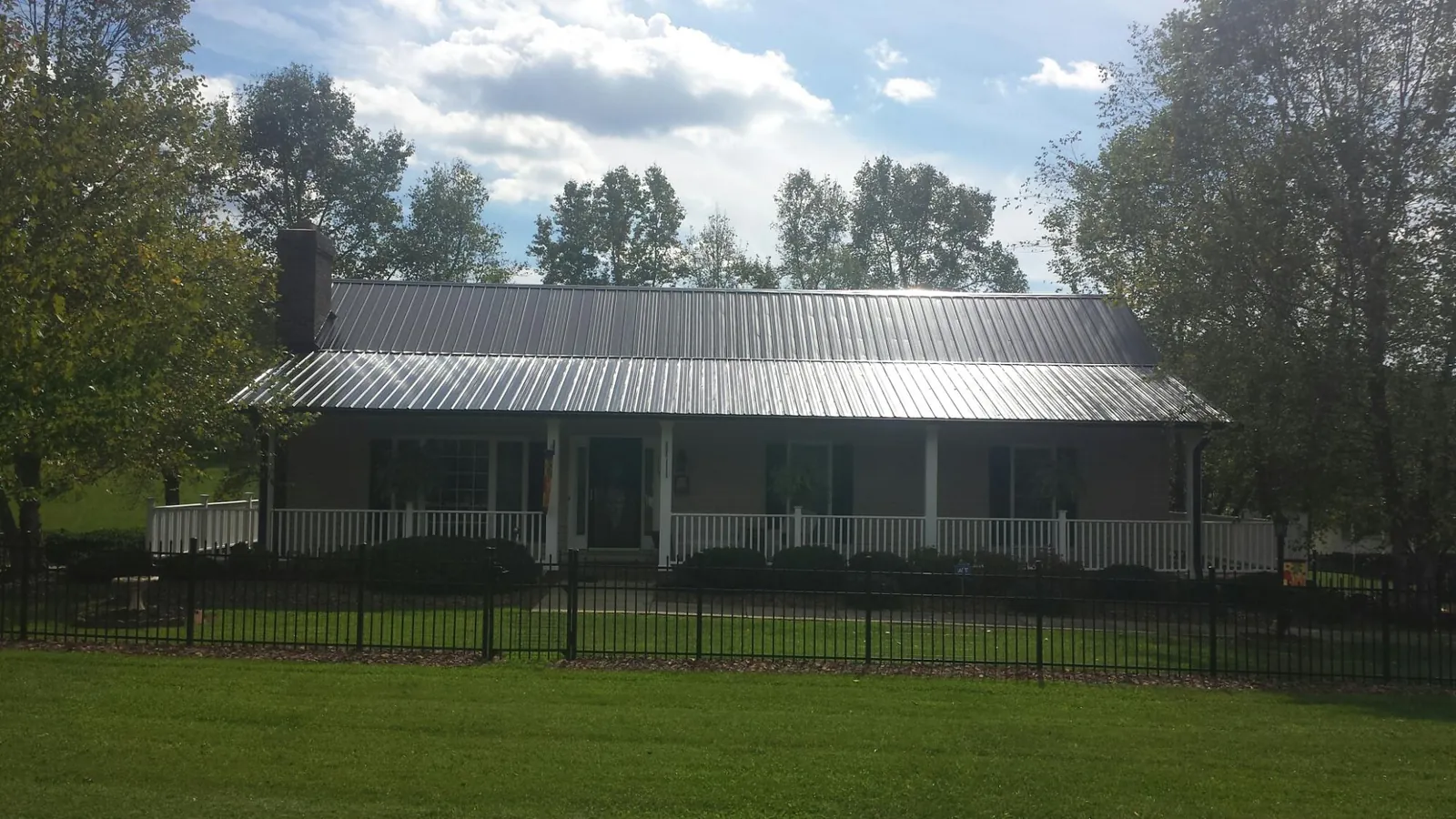 Gray metal roof on a brick ranch with a full width front porch — Gutter Guard Installation work by our crew in Louvale
