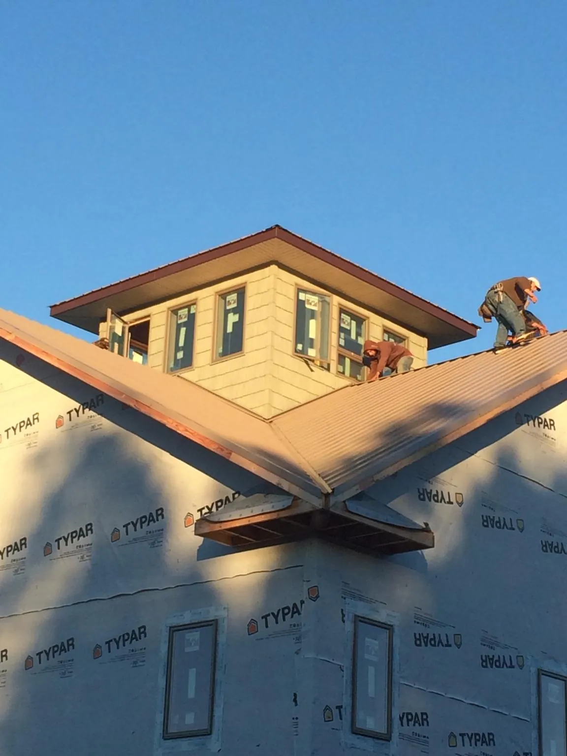 Roofers working around a rooftop cupola on a new metal roof at sunset — Roof Waterproofing in Louvale by Roofing Brothers